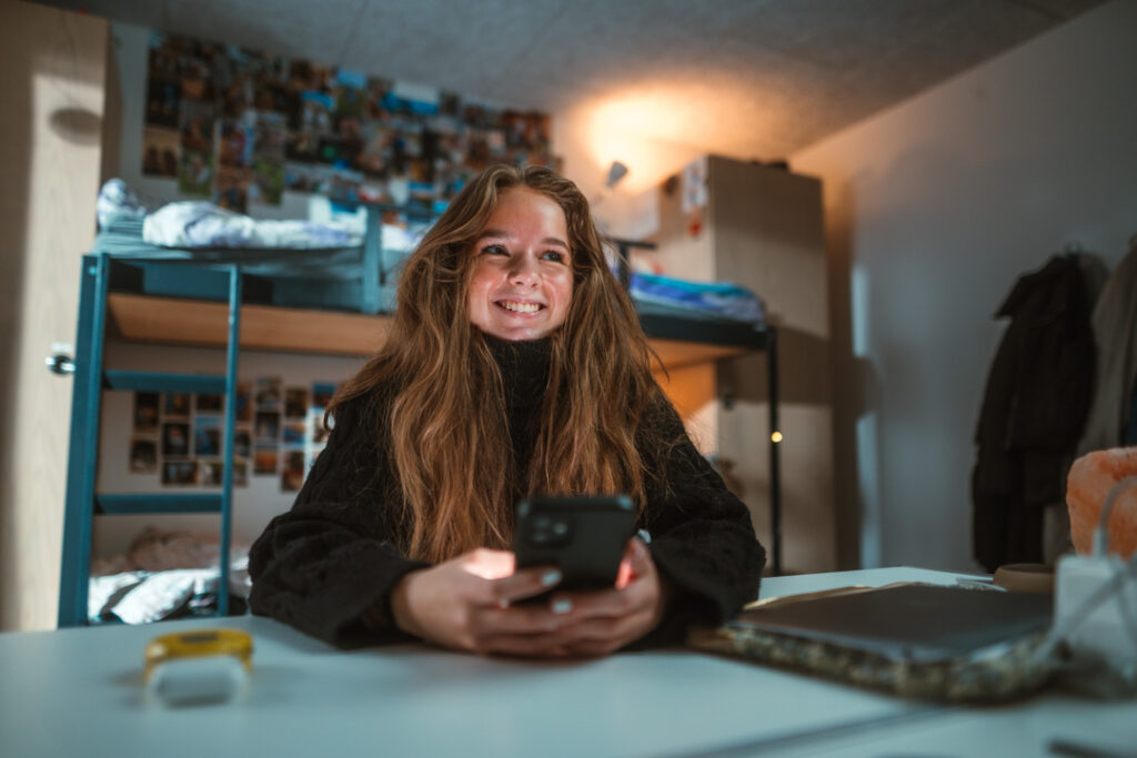 Efterskoleelev læser beskeder i Zenbi på mobilen – digital skolekommunikation i hverdagen på efterskolen.